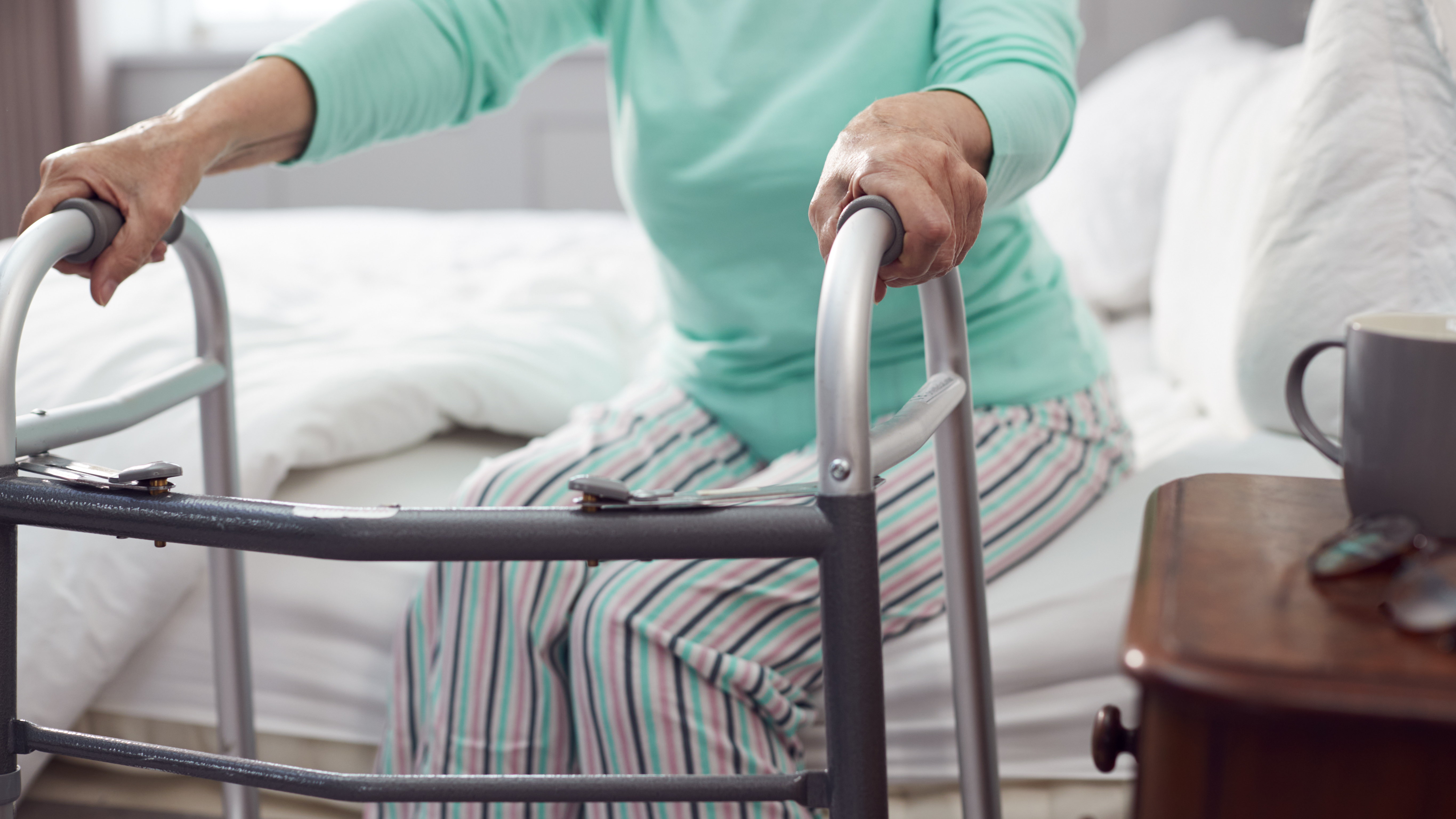 Close Up Of Senior Woman At Home Using Walking Frame To Get Out Of Bed